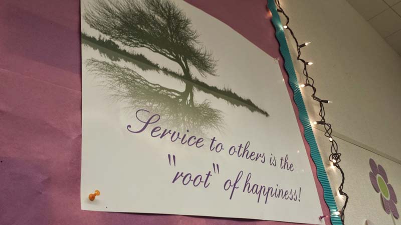 "Service to others is the root of happiness" sign